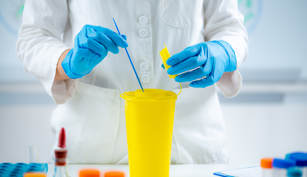 Deux mains gantées bleues mélangent du liquide dans un contenant jaune